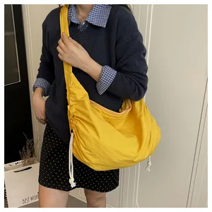 Detail of yellow nylon dumpling bag with scrunchie texture and drawstrings on the side