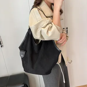 Détail du grand sac cabas en daim noir avec finitions en cuir et accessoire mini pochette