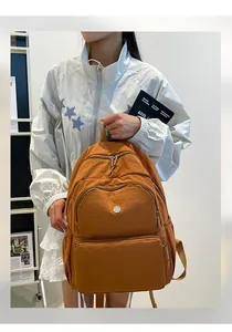Dettaglio dello zaino in nylon caramello con scomparti funzionali e cerniere multiple