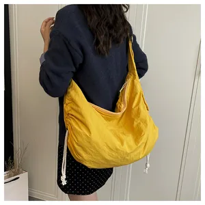 Detail of bright yellow nylon hobo bag with side drawstring and wide shoulder strap
