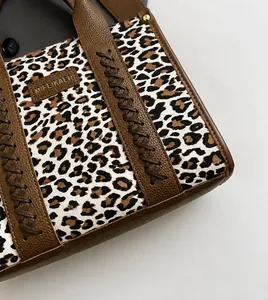 Nahaufnahme von Canvas mit Leopardenmuster und braunem Kunstleder an der Handtasche