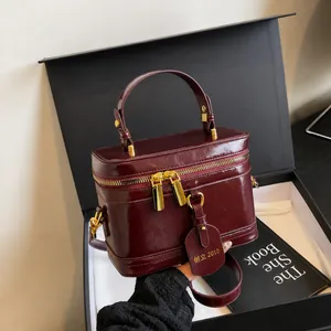 Detail der burgunderfarbenen Kosmetiktasche aus Leder mit goldenem Reißverschluss