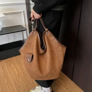 Détail du sac cabas en daim caramel foncé avec texture souple et garniture en cuir sur l'anse