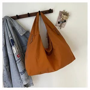 Dettaglio di borsa tote in nylon arancione con tasca a zip su gancio in legno