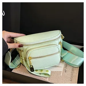 Dettaglio borsa a sella verde chiaro con zip multiple e finiture in metallo dorato