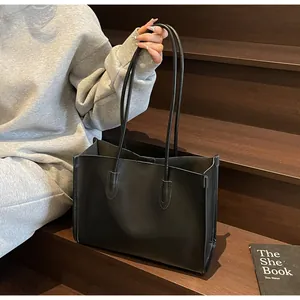 Detail shot of a minimalist black soft leather large capacity shoulder tote bag.