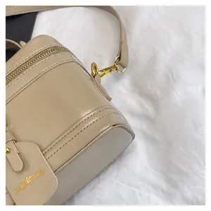 Detailansicht der beigefarbenen Handtasche mit Metallhaken und abnehmbarem Schultergurt