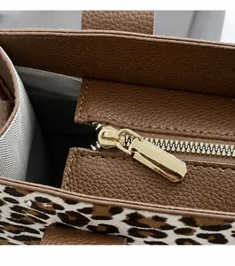 Nahaufnahme von Leopardenstoff und Ledertextur mit goldenem Reißverschluss an Damenhandtasche