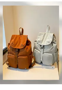 Dettaglio di zaini in nylon capienti nei colori marrone arancio e grigio beige chiaro