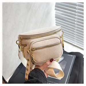 Dettaglio della borsa a tracolla bianco crema con borchie dorate e texture con zip