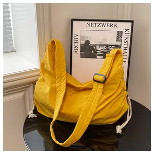 Macro shot of yellow nylon hobo bag featuring crinkled texture and white drawstring detail
