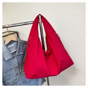 Dettaglio della borsa tote in nylon rosso con ampie tasche laterali e tessuto morbido