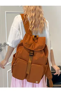 Zaino in nylon marrone caramello con tasche multiple indossato da una modella alla moda