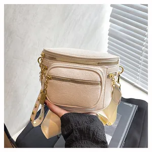 Dettaglio borsa a tracolla in pelle crema testurizzata con hardware dorato e zip multiple