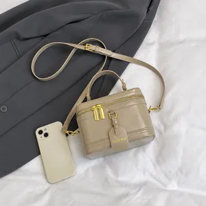 Draufsicht auf eine khakifarbene Umhängetasche mit Goldzipper und Smartphone als Größenvergleich