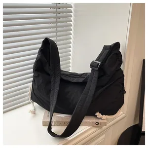 Detail of black nylon pleated crossbody bag with white cotton drawstring and wide strap