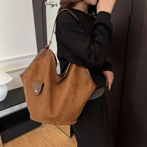 Vue latérale d'un grand sac fourre-tout en daim marron avec petite poche décorative