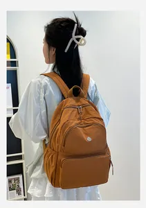 Dettaglio dello zaino in nylon marrone caramello con tasche multiple con zip sul retro