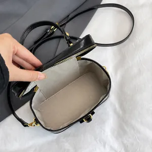 Detail der Box-Umhängetasche mit schwarzem Lackfinish und Fischgrätfutter