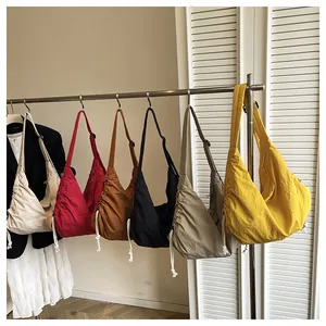 Selection of multi-colored large nylon crescent crossbody bags hanging on a rack