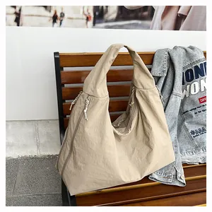 Vista dettagliata della borsa tote beige in nylon leggero su una panca in legno all'aperto
