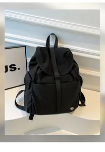 Dettaglio dello zaino nero in nylon impermeabile con chiusura a fibbia e logo in metallo