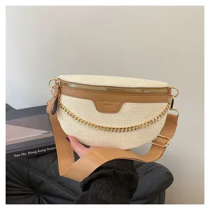 Vue détaillée de l'imprimé crocodile gaufré et de la chaîne dorée sur le sac banane blanc