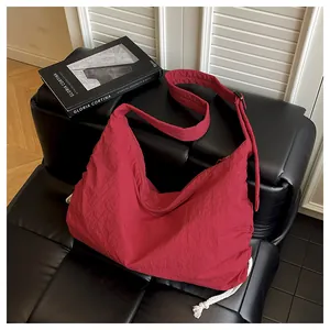 Detail of red nylon crescent bag on black leather sofa with white drawstring decor
