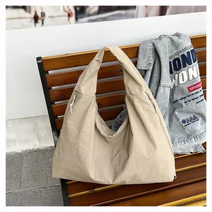 Dettaglio di una borsa tote beige in nylon con trama a coulisse su una panchina