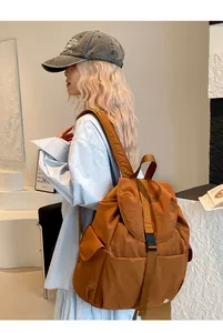Dettaglio di zaino in nylon marrone con chiusura a fibbia, patta e tasca laterale