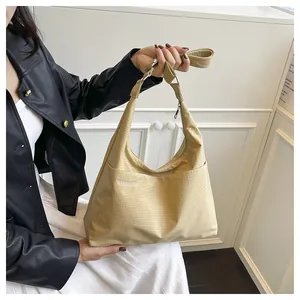 Détail du sac cabas kaki clair montrant la texture quadrillée et la bandoulière réglable