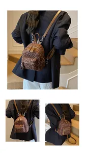 Detail view of mini leopard print backpack with brown straps and functional zipper pockets