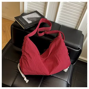 Macro detail of wine red nylon crossbody bag with pleated texture and adjustable strap