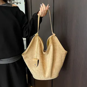 Détail du sac cabas en daim kaki avec ouverture en pétale et breloque en cuir élégante