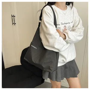 Détail d'un grand sac fourre-tout à carreaux avec une large bandoulière souple