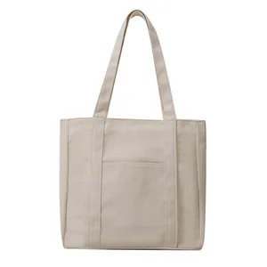 Minimalist beige canvas tote bag with thick handles and outer pocket on white background