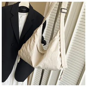 Detail view of large cream nylon hobo bag featuring ruched texture and adjustable strap