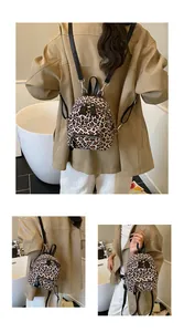 Detail shot of leopard print mini backpack showing zip pockets and black leather straps