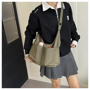 Détail du sac cabas à carreaux vert foncé montrant les poches avant et la texture de la toile
