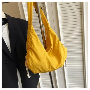 Detail of yellow nylon crescent bag with white side drawstrings and wide shoulder strap