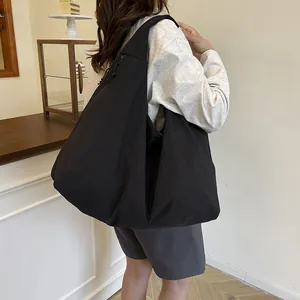 Borsa tote in nylon nero con trama a pieghe e tracolla larga, mostrata sul modello