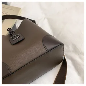 Dettaglio borsa hobo in pelle marrone con fibbia a D in metallo e finitura martellata