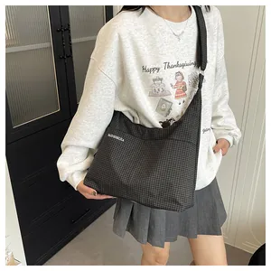Vue détaillée d'un grand sac fourre-tout en toile à carreaux noir et blanc avec bandoulière
