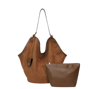 Détail du grand sac cabas en daim marron avec une pochette zippée et un charme de cœur