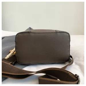Dettagli di una borsa a secchiello in pelle marrone con tracolla larga e perline