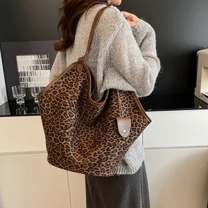Gros plan détaillé du sac cabas léopard avec bordure en cuir marron et breloque décorative