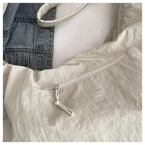 Detail view of large nylon crossbody bag showing side zipper and textured fabric