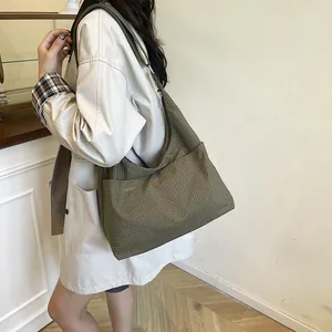 Sac cabas hobo minimaliste vert foncé à carreaux avec large bandoulière porté par un modèle