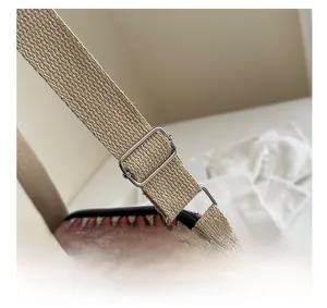 Detail showing adjustable strap with silver metal buckle on woven geometric crossbody bag