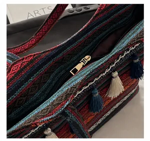 Detail showing the zipper closure and colorful woven pattern with blue fringe tassel